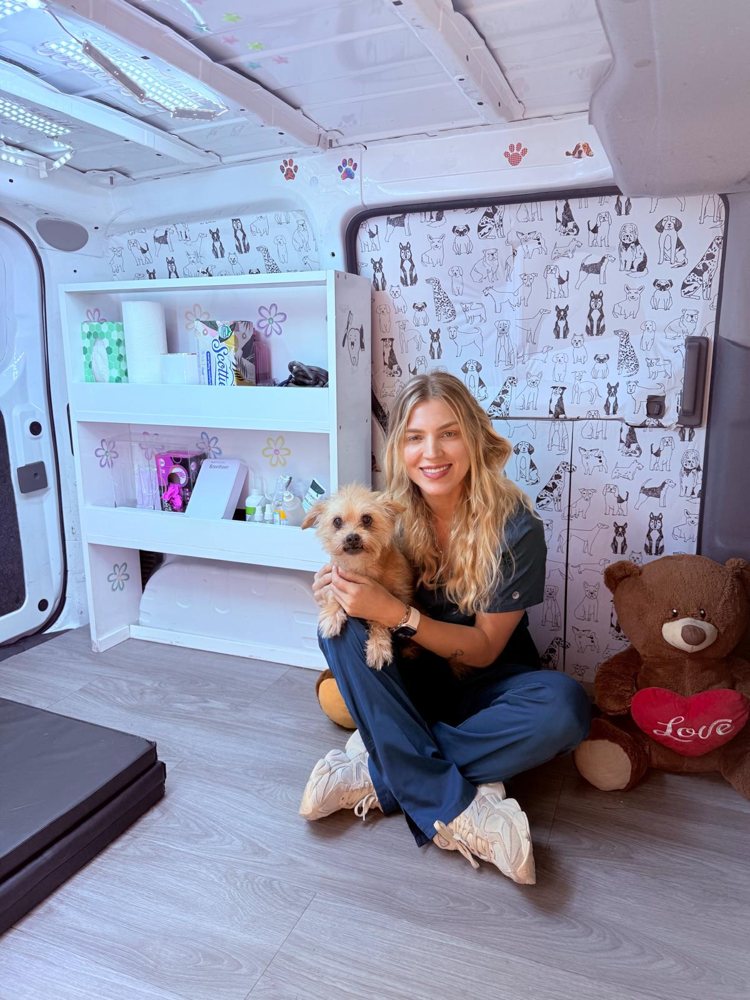 Ana Bueno inside the Pet Smile mobile unit holding a small dog